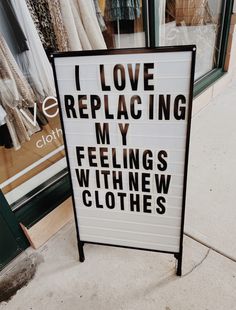 a sign that says i love replacing my feeling's with new clothes in front of a store