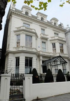 a large white building with many windows and balconies on the top floor, next to a black iron fence