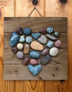 a heart made out of rocks sitting on top of a wooden board