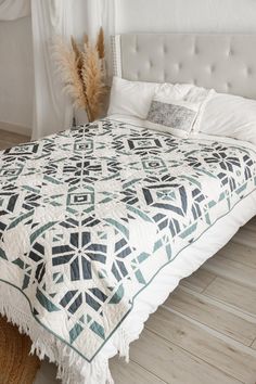 a bed with a white and blue quilt on it