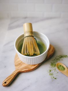 a wooden whisk in a white bowl with green tea