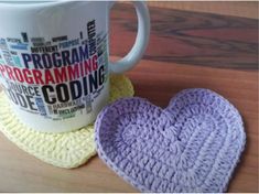 a coffee cup with a crocheted heart next to it