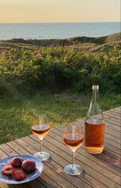 two glasses of wine sitting on top of a wooden table next to an empty bottle