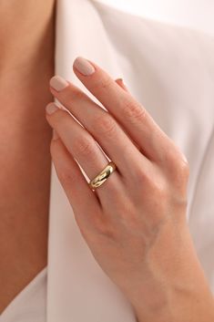 a woman's hand with a gold ring on her left hand, wearing a white shirt