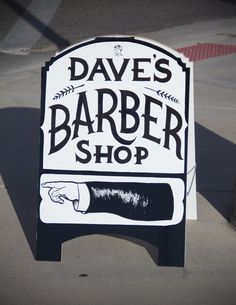 a sign advertising a barber shop on the sidewalk