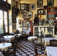 the inside of a restaurant with checkered tables and white tablecloths, framed pictures on the wall