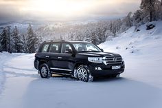 the suv is parked in the snow near mountains