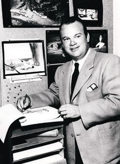 a black and white photo of a man in a suit writing on a piece of paper