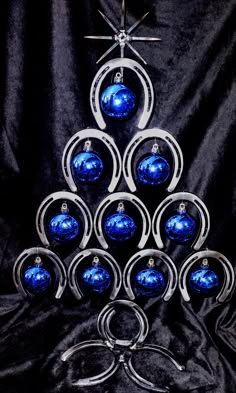 a christmas tree made out of blue glass balls and silver metal scissors on a black background