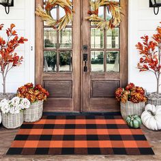 the front door is decorated for fall with pumpkins and gourds in baskets