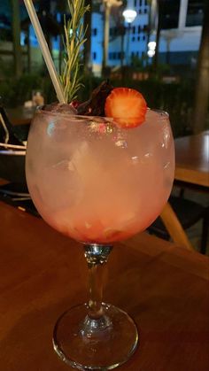 a drink in a wine glass with strawberries on the rim and garnish