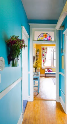 the hallway is painted bright blue and has flowers in vases on either side of the door