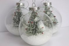 three glass ornaments with snow and trees in them