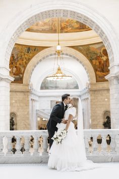 a bride and groom kissing in front of an ornate archway