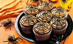 cupcakes decorated with chocolate icing and spooky spider decorations on a plate