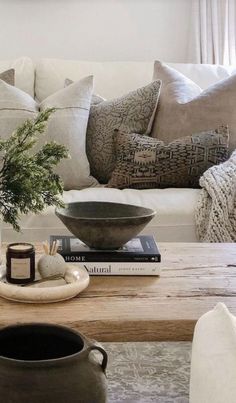 a coffee table with vases and books on it in front of a white couch