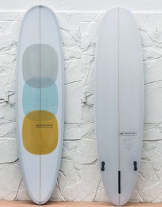 two surfboards standing up against a white brick wall with circles on the bottom and sides