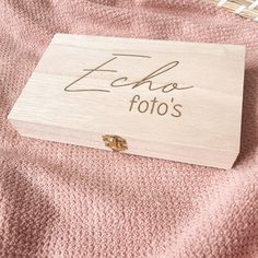 a wooden box with the word echo fotos written on it sitting on a pink blanket