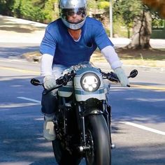 a man riding on the back of a motorcycle down a curvy road with trees in the background