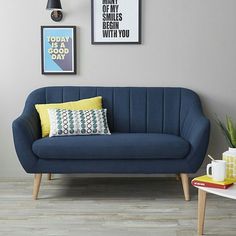 a blue couch sitting next to a table with two coffee mugs on top of it