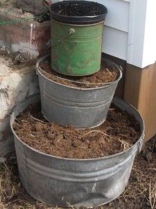 three metal buckets filled with dirt next to a door