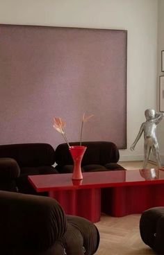 a living room filled with furniture and a statue on top of a red coffee table