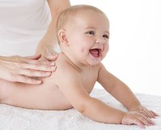 a baby being massaged by an adult on a white blanket with her hands in the air