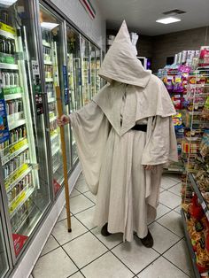 a man in a white robe and hat with a cane standing next to a refrigerator