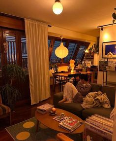 a man sitting on top of a couch in a living room next to a window