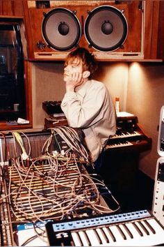 a man sitting in front of a bunch of electronic equipment with his hands on his face