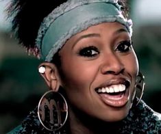 a close up of a person wearing large earrings and a headband with feathers on it