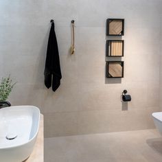 a bathroom with a sink, towel rack and toilet paper dispenser on the wall