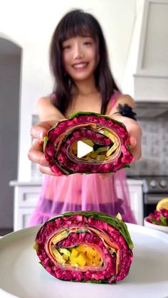 a woman in a pink dress is holding up some food