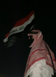 a man with a scarf on his head is standing in front of an egyptian flag