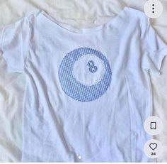 a white shirt with a blue circle on the front and bottom that has an eight in it's center