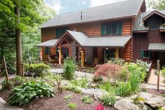 a large log house surrounded by trees and flowers