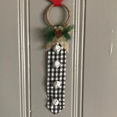 a door hanger with a plaid tie and a pine cone hanging from it's side