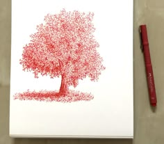 a red pen sitting next to a drawing of a tree