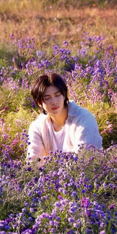 a woman laying in the middle of a field of purple flowers