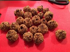 a bunch of oatmeal balls on a red cutting board next to a pair of scissors