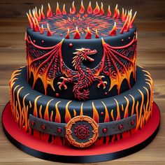 a three tiered cake decorated with flames and a dragon on the top, sitting on a wooden table