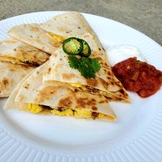 three quesadillas on a white plate with salsa and ketchup