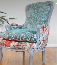 an ornate chair and footstool in front of a potted plant on a hard wood floor