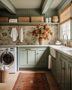 a washer and dryer in a room with green cabinets, flowers on the wall