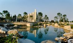 a pond surrounded by rocks and trees in front of a building