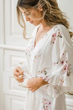 a woman wearing a white blouse with pink flowers on it