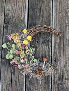 a wreath made out of branches and flowers on a wooden surface with pine cones, mushrooms, and other plants