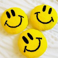 three yellow smiley face pillows sitting on top of a bed