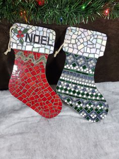 two mosaic christmas stockings hanging from a tree