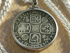 an old silver pendant with symbols on it, sitting on a white necklace link chain